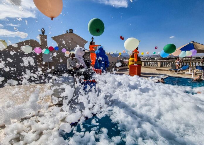 Fiesta de la espuma en la piscina de un hotel en Sharm el-Sheij con globos de colores, animadores disfrazados de personajes y niños jugando