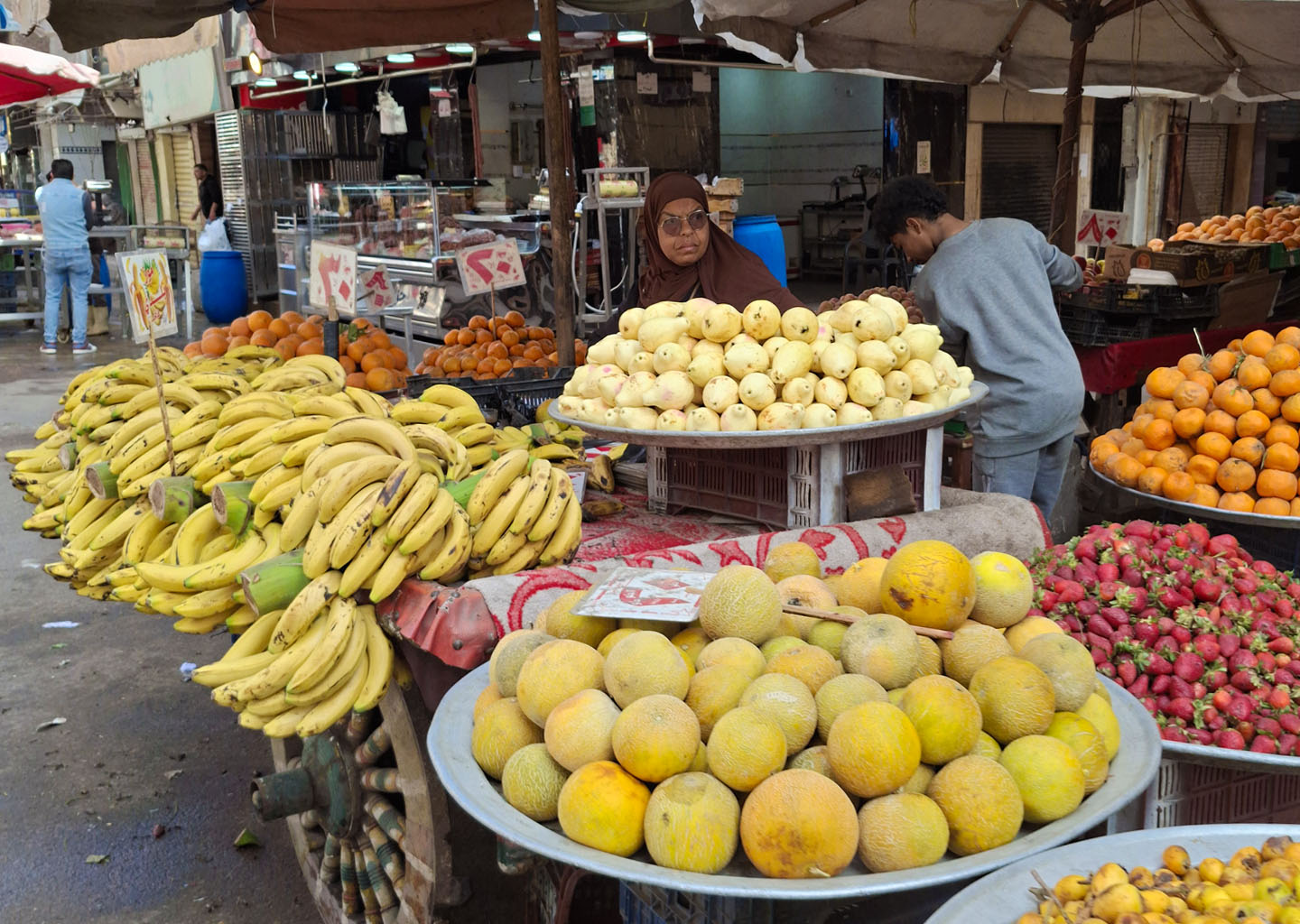 Un puesto callejero tradicional en Egipto con exhibición de frutas frescas y baratas como plátanos, melones y fresas