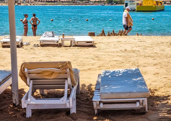 Tumbonas de playa en la arena dorada con vistas al mar turquesa en Sharm el-Sheij durante el invierno en Egipto
